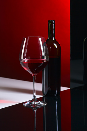 bottle and glass with red wine on  dark background